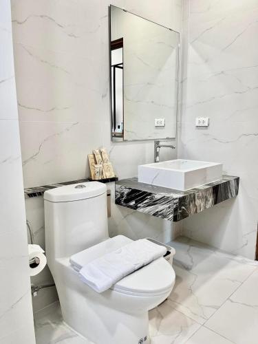 a white bathroom with a toilet and a sink at Ozone hotel khanom in Ban Phang Phrao