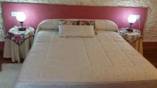 a large white bed with two side tables at Posada de Los Aceiteros in Ahigal de los Aceiteros