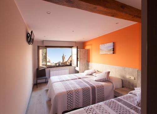 2 Betten in einem Zimmer mit orangefarbener Wand in der Unterkunft Pensión San Lorenzo in Nájera