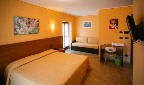 a bedroom with a bed and a desk and a couch at Albergo dei Pescatori in Chiusa di Pesio