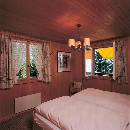 ein Schlafzimmer mit einem Bett und zwei Fenstern in der Unterkunft Rigirolle in Rigi Kaltbad