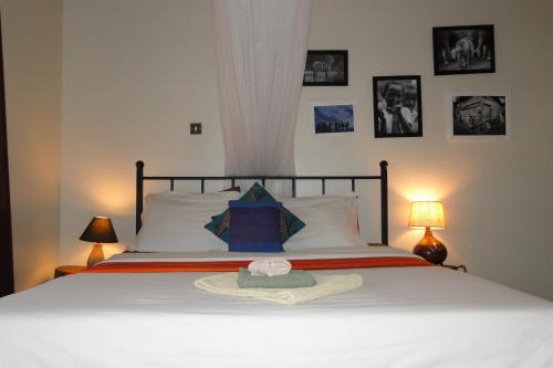 een slaapkamer met een bed met een hoed erop bij Carpe Diem Guesthouse in Entebbe