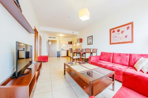 a living room with a red couch and a table at Olympic Park I, Sun & Snow in Kołobrzeg