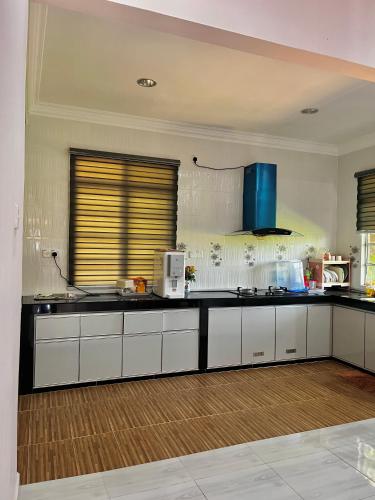 a large kitchen with white cabinets and a blueettel at Ramly Homestay in Kuala Terengganu