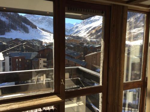 a view of a snowy mountain through a window at Appartement vue 180° sur massif in Val dʼIsère