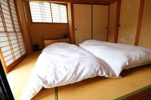 two white beds in a room with two windows at 郡上八幡 貸宿 GujoHachiman Kashiyado ICHI in Gujo