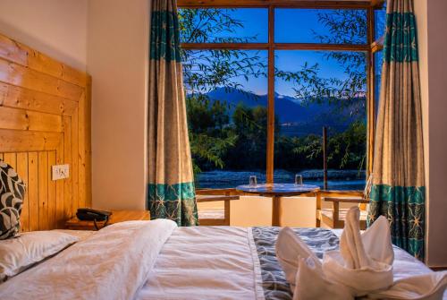 a bedroom with a bed and a large window at The Nature Residency - A Riverside Resort in Leh in Leh