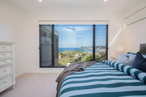 a bedroom with a bed and a large window at Avoca Infinity - Expansive Haven with Ocean Panorama in Terrigal