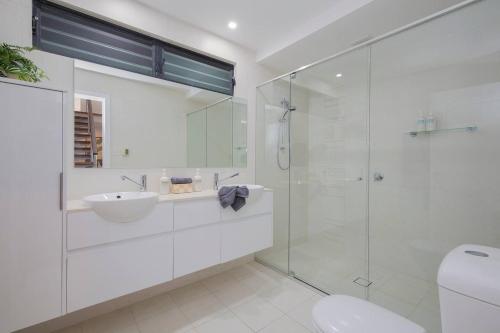 a bathroom with a glass shower and a sink at Avoca Infinity - Expansive Haven with Ocean Panorama in Terrigal