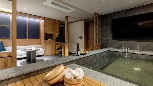 a bathroom with a tub with a tv and a bath room at Anook Resort & Spa Busan Haeundae in Busan