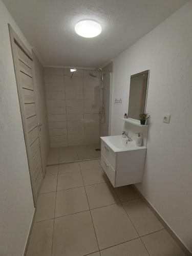 a white bathroom with a sink and a mirror at Rio rooms in Băile Herculane