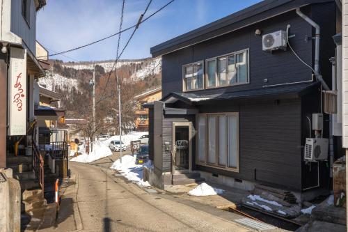 a black house on the side of a street at Kalik House in Nozawa Onsen