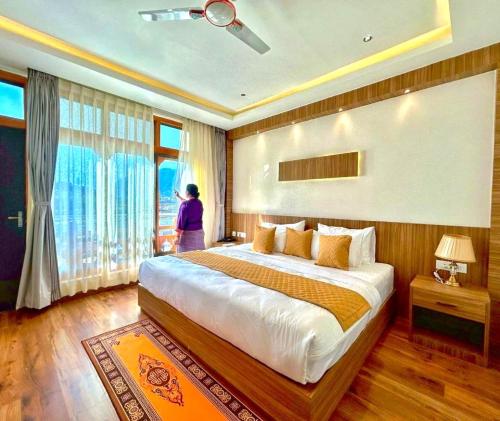 a bedroom with a large bed with a woman in the window at Dema Rresort in Paro