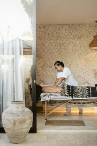 a woman sitting on a bed in a room at Karma House Ungasan in Jimbaran