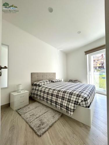 a white bedroom with a bed and a window at Figueira River House in Bragança