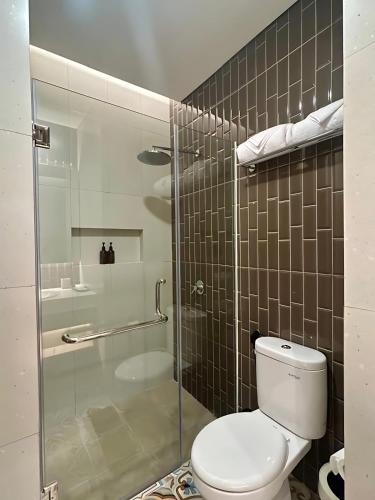 a bathroom with a toilet and a glass shower at Kaloka City Hotel Bima in Bima