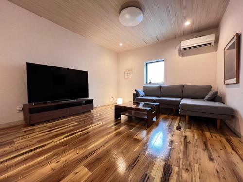 a living room with a couch and a flat screen tv at 内町3階 高松中心地 広いメゾネット貸切 2ベッドルーム 最大4名 in Takamatsu