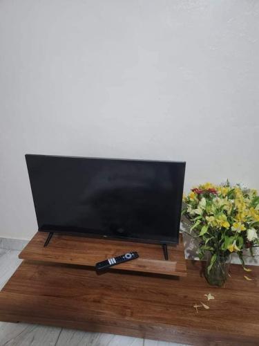 a television on a wooden stand with a remote control at Muthiga Springs in Kikuyu