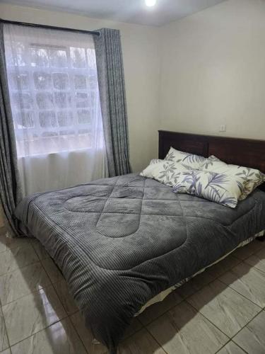 a large bed in a bedroom with a window at Muthiga Springs in Kikuyu