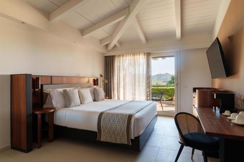 a hotel room with a bed and a balcony at Baia Di Chia Resort Sardinia, Curio Collection By Hilton in Chia
