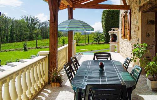 a patio with a green table and chairs and an umbrella at Ancienne Forge Avec Piscine in Saint-Mesmin