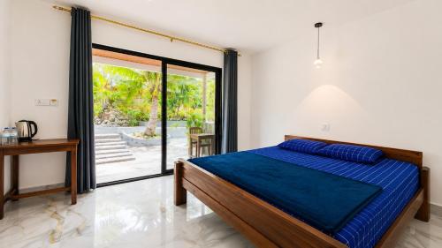 a bedroom with a bed and a sliding glass door at Garden Hostel Koh Rong in Koh Rong Island