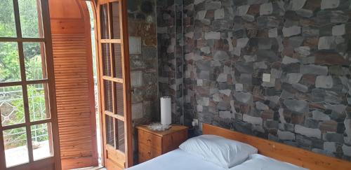 a bedroom with a bed and a stone wall at Eco wellness the arch in Lévktron