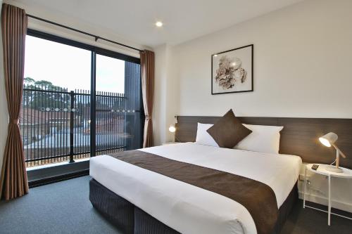 a bedroom with a large bed and a large window at Quality Apartments Dandenong in Dandenong