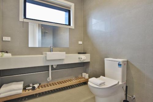 a bathroom with a toilet and a sink and a mirror at Quality Apartments Dandenong in Dandenong