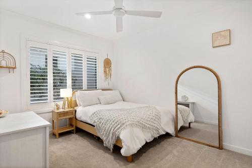 a white bedroom with a bed and a mirror at Tallows Coastal Retreat in Kingscliff