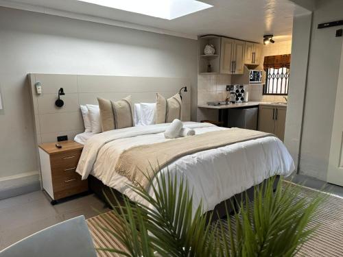 ein Schlafzimmer mit einem großen Bett und eine Küche in der Unterkunft Koi liv-Inn Bedfordview ll Modern Guest House Near OR Tambo in Bedfordview