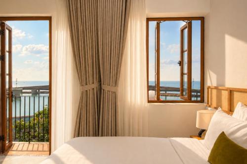 a bedroom with a bed and a window with a view at Noska Hotel Sunset Town Sea View & Fireworks in Phú Quốc