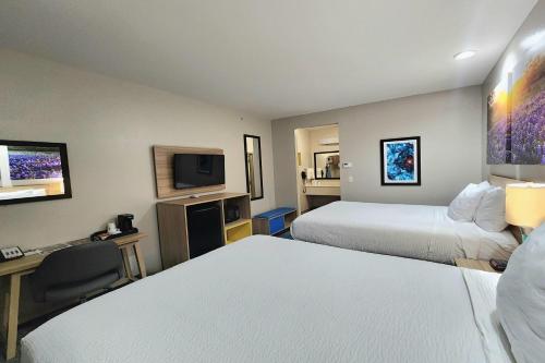a hotel room with two beds and a television at Days Inn & Suites by Wyndham Katy in Katy