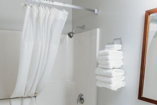 a bathroom with a shower with a stack of towels at Travelodge by Wyndham Worland in Worland