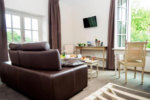 a living room with a brown leather couch and a table at Le Germinal in Cesson-Sévigné