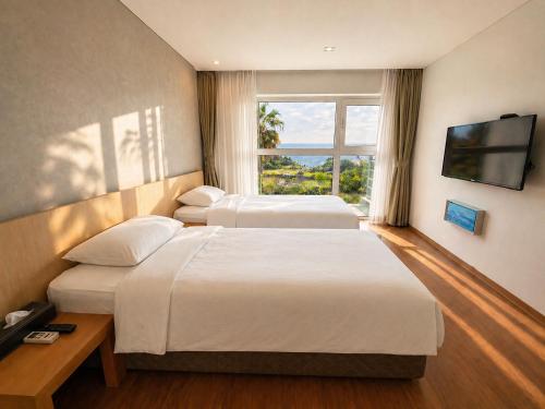 a hotel room with three beds and a television at Y Resort Jeju in Seogwipo