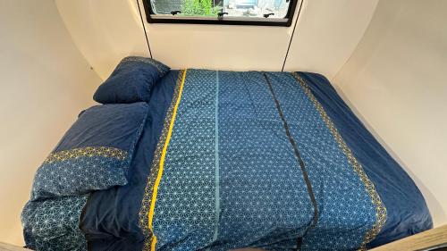 a blue bed in a room with a window at La caravane de Camille & Piscine in Soulaires