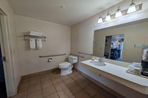a bathroom with a toilet and a sink and a mirror at Olive Tree Inn & Suites, a Howard Johnson by Wyndham in San Luis Obispo