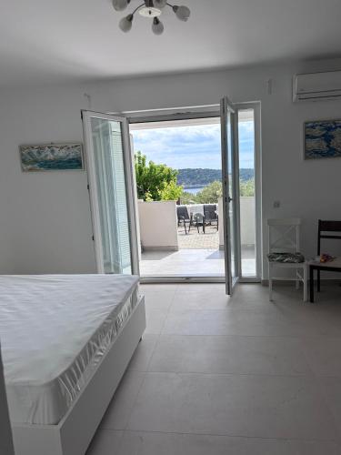 a white bedroom with a bed and a sliding glass door at Apartment Zekija in Barbat na Rabu