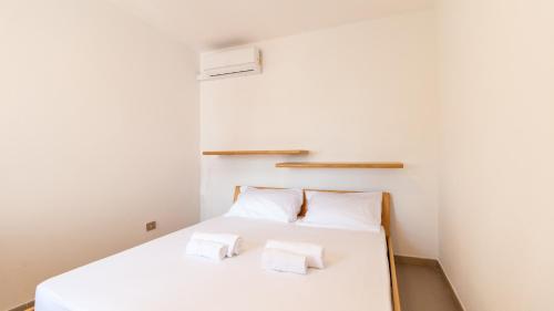 a bedroom with a white bed with two towels at Golden Sunset - S'Archittu in S'archittu Cuglieri
