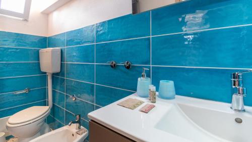 a blue tiled bathroom with a toilet and a sink at Golden Sunset - S'Archittu in S'archittu Cuglieri