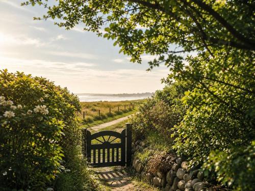 a gate leading down a dirt road with a pathway at Ferienhaus Klenterdeel in Keitum