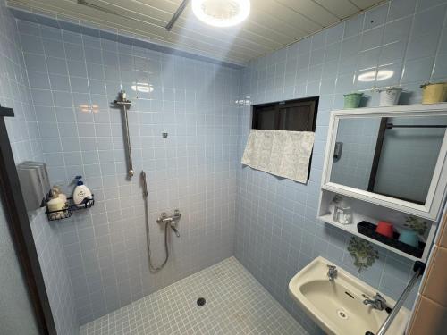 a blue tiled bathroom with a shower and a sink at Green Hights Residence-101 in Naha