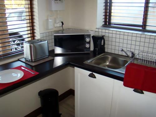 a kitchen with a sink and a microwave at Zamar Guest House in Caledon