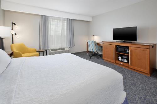 a hotel room with a bed and a flat screen tv at Hampton Inn by Hilton West Bloomfield Novi in Farmington Hills