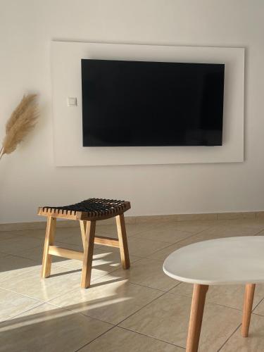 a living room with a table and a flat screen tv at Pnoe Home in Kavála