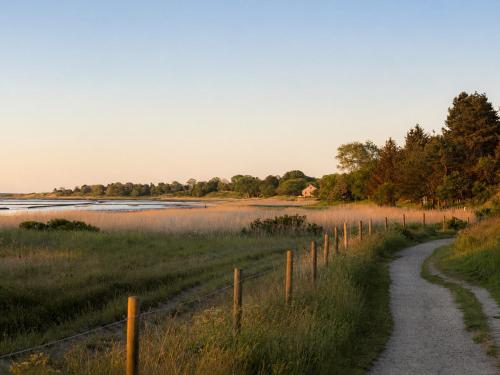 a dirt road next to a river with a fence at Ferienhaus Klenterdeel in Keitum