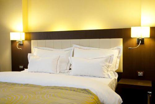 a bedroom with a large bed with white pillows at Hotel Pietroasa in Buzau