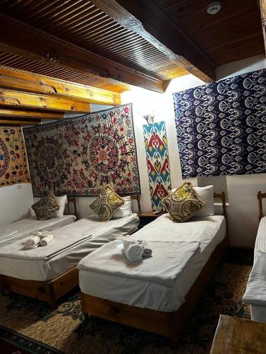 two beds in a room with paintings on the wall at Caravan Sarai XV century Mextar Ambar old town in Bukhara
