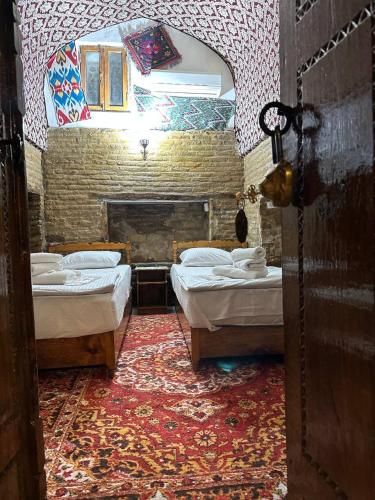 a room with two beds and a brick wall at Caravan Sarai XV century Mextar Ambar old town in Bukhara